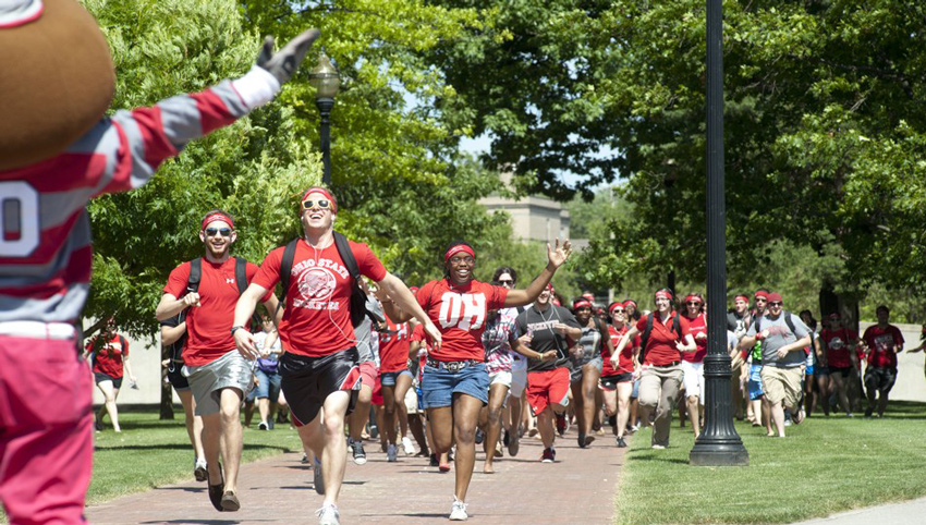 Cadets running on campus while Brutus Buckeye cheers them on.
