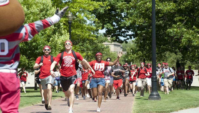 Cadets running on campus while Brutus Buckeye cheers them on.