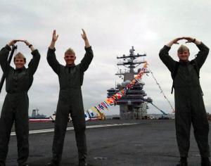 Navy officers spell out O-H-I-O on an aircraft carrier at sea.