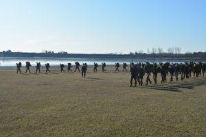 ROTC cadets marching in formation along a small body of water.