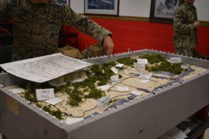 ROTC cadet observing both the table and paper map. 